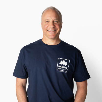 Man wearing a navy blue t-shirt with a Pacific Shaving Company logo on a white background.