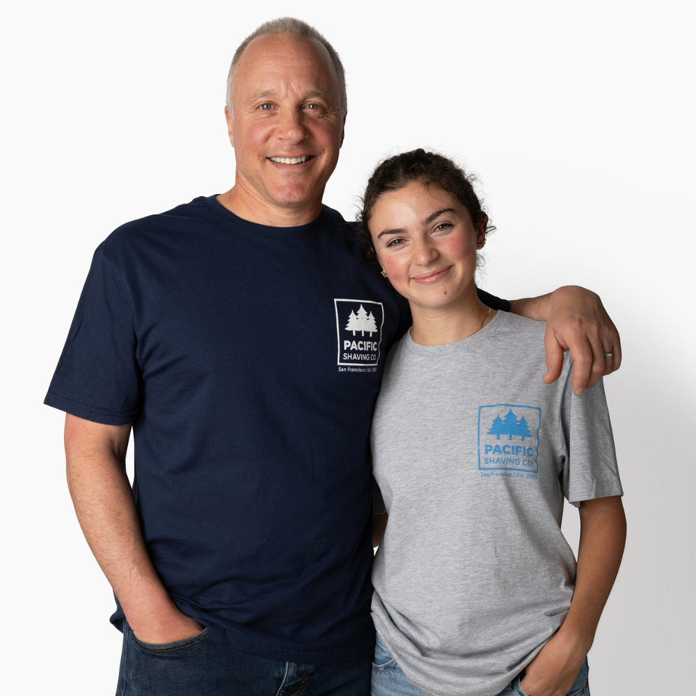 Man and woman wearing navy and gray t-shirts with Pacific Shaving Company logo on a white background